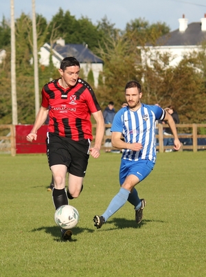On the ball: Joe Lawless looks to get the ball away despite the pressure of Benny Lavelle. Photo: Ballina Town Facebook 