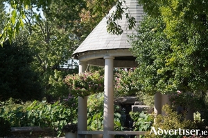 A roofed gazebo makes a lovely focal point surrounded by pretty planting.