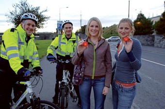 Students Cliona Fitzpatrick and Carmel Moran receive clip-on flashing lights from Community Garda Vincent Kelly and Garda Ivan Cunnane. The gardaí will be distributing these lights throughout the city over the next two weeks.