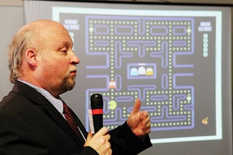 Dr Chris Coughlan of Hewlett-Packard speaking in the Computer & Communications Museum, NUI Galway, with Pacman playing in the background.