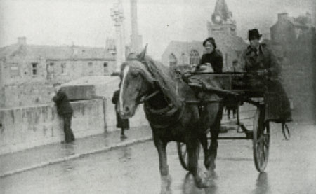 Postin&rsquo; in Galway: Willie John Pat with a passenger on his sidecar on O&rsquo;Brien&rsquo;s Bridge (apologies for poor photograph).