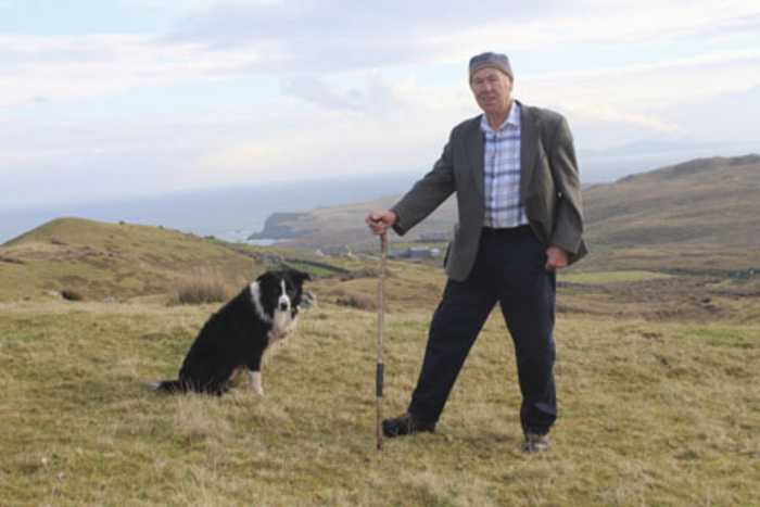 Patrick and his dog Breeze against a backdrop of the scenic Clare Island landscape that has inspired his singing. 