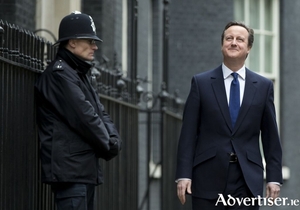 UK prime minister David Cameron walks along Downing Street, while a British bobby watches on.