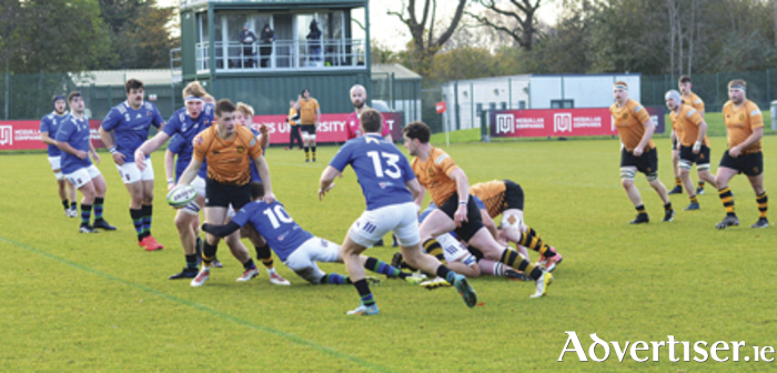 Buccaneers Stephen Mannion gets the ball away to Frank Hopkins despite the best being pressurised by James Humphreys of Queen’s University during the AIL Division 1B clash in Belfast on Saturday
