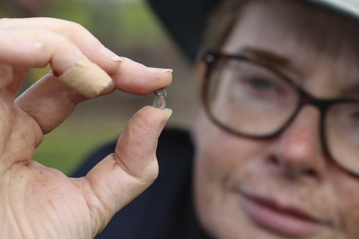 Dr Michelle Comber holding a turquoise and red glass bead found at the Rathgurreen Ringfort and believed to date from Early Medieval Ireland