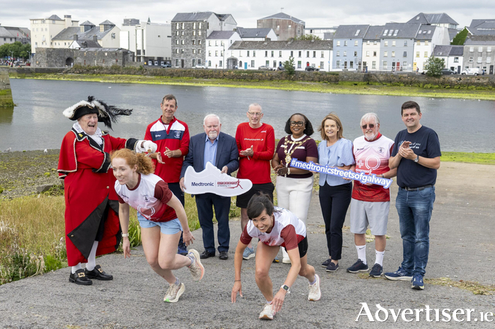 Mayor of Galway Helen Ogbu with (from left) Liam Silke, Town Crier; Seamus Lynch, Chair, Galway City Harriers; Cllr Donal Lyons, Brian Bruton, Race Director; Cllr Clodagh Higgins; Mick Roche - original 1986 founding committee; Keith Healy Medtronic; as GCH athletes Caoimhe Daniels and Nora Tierney show how it&rsquo;s done  for Medtronic Streets of Galway 8K.